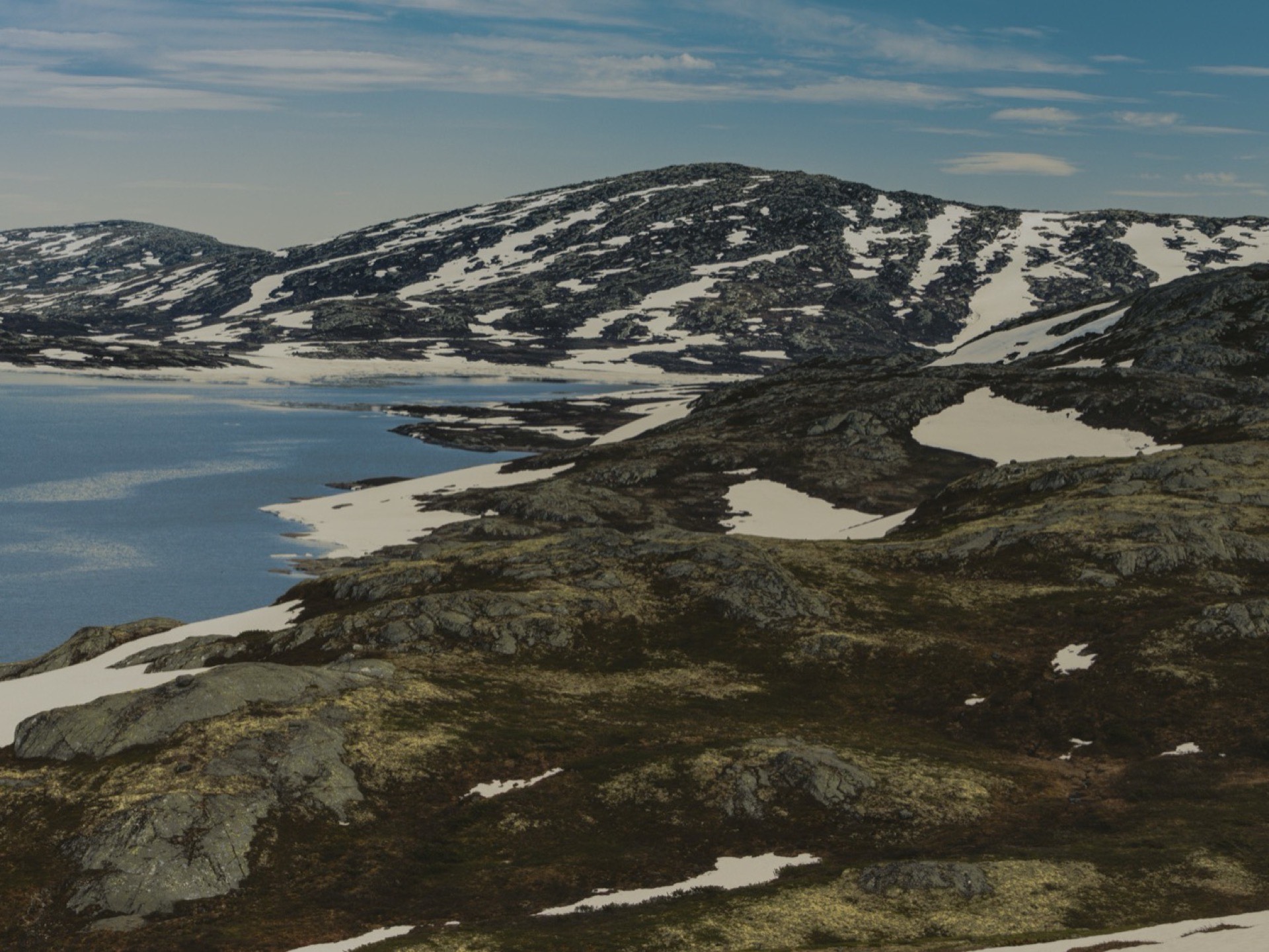 Jezioro i pola śnieżne na wysokogórskim płaskowyżu Jotunheimen